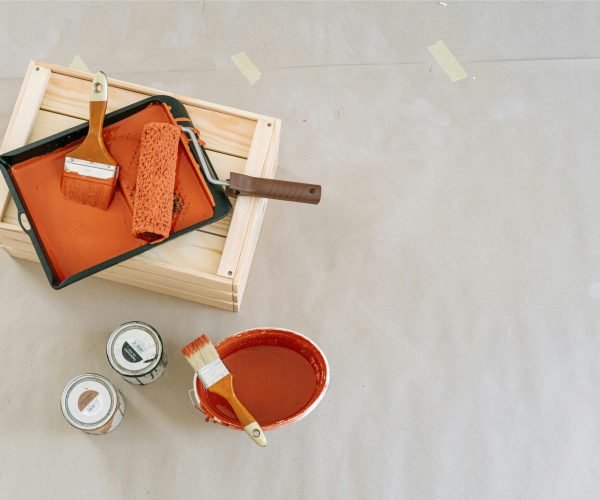 This image is used in kitchen painting section to show the professional products used in the painting process. Buckets of paint, a paint roller and two paint brushes are shown in this image.